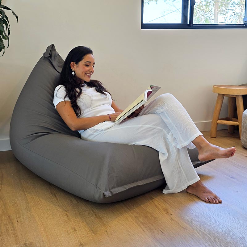 Mocha Cotton Canvas Triangle Bean Bag Chair by Mooi Living in a living room setting, Our beautiful model seated and reading a book.