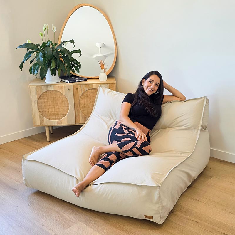 Woman seated on the Natural Double Boss oversized bean bag with removable cover by Mooi Living.