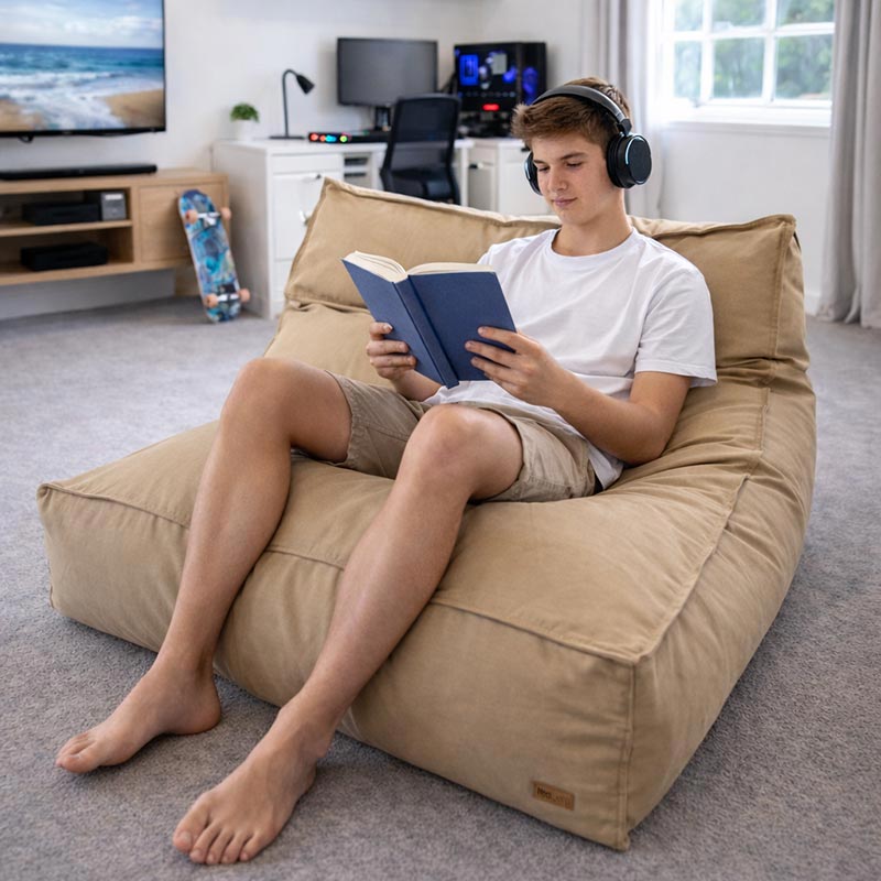 A teenager sitting comfortably in a Tanned Double Boss Bean Bag reading.