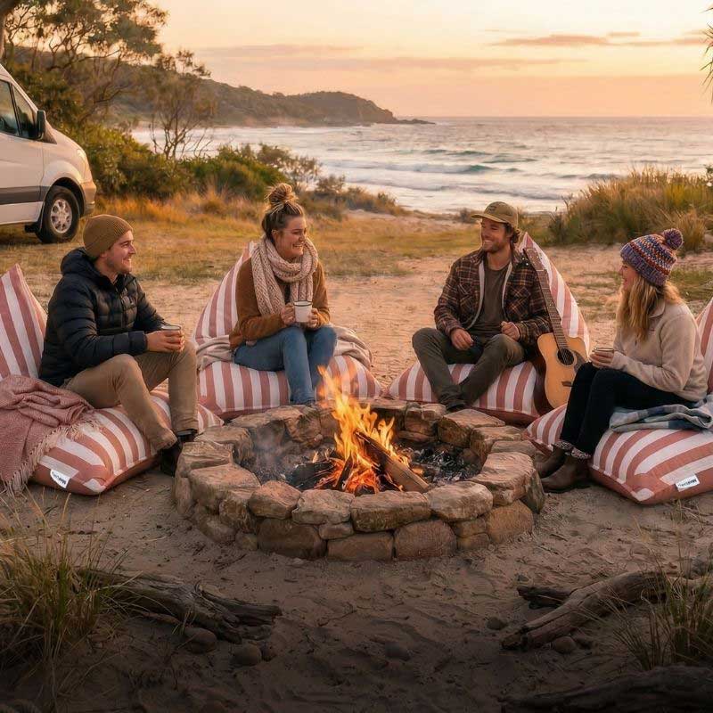 Group of friends relaxing on blush stripe outdoor reversible triangle bean bags, outdoor bean bag by Mooi Living while camping outdoors.