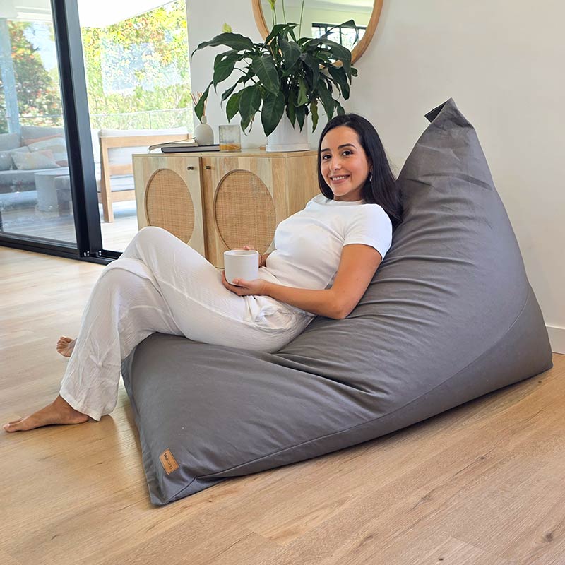 Mocha oversized Cotton Canvas Triangle Indoor Bean Bag Chair by Mooi Living in a modern living room, a lady seated enjoying a coffee.