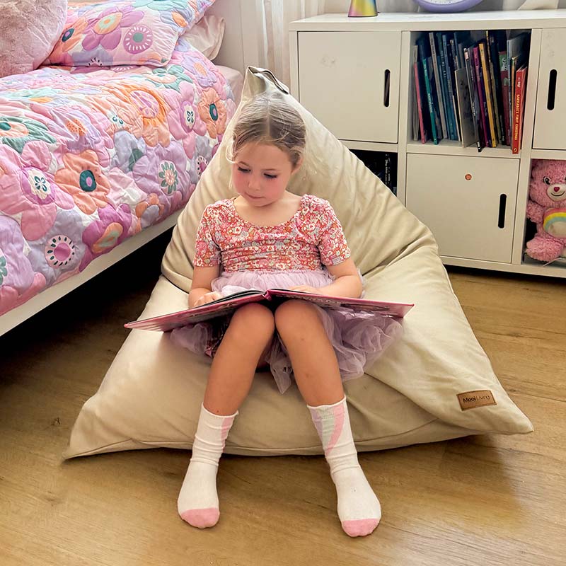100% Cotton Canvas Mini Triangles in Natural indoor bean bag by Mooi Living with a young girl sitting and reading a book.