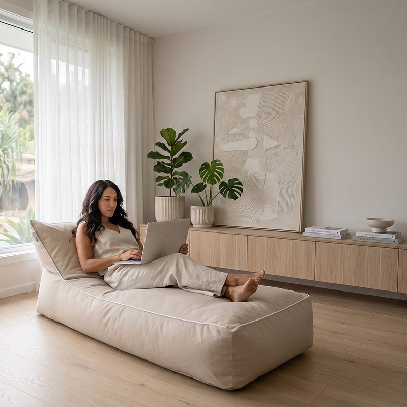 Woman using a laptop on a Talia Float outdoor bean bag by Mooi Living, styled in a modern living room.