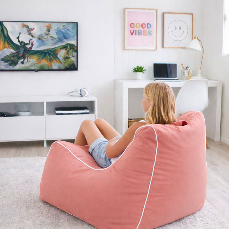 Blush Bora Bora outdoor bean bag used indoors, styled in a bright modern living room with a woman relaxing comfortably while watching TV