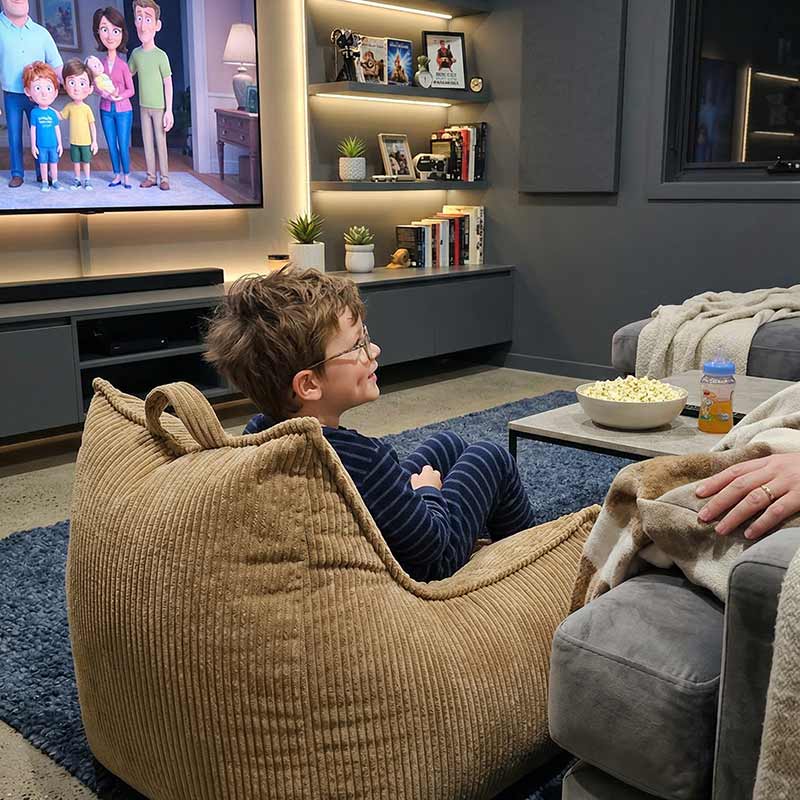 Lifestyle image of the Mini Cord Chair indoor bean bag by Mooi Living in Caramel with a little boy in a theatre room.