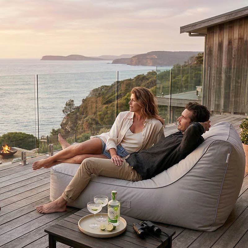 Lifestyle Image of the Lachlan Sunlounger  outdoor bean bag by Mooi Livingin Natural Beige with a couple relaxing on the bean bag by the ocean at sunset.