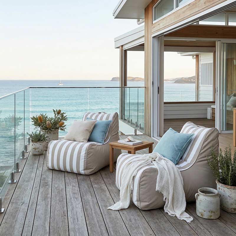 Lifestyle Image - 2 Bora Bora Bean Bag Chairs outdoor bean bag by Mooi Living styled with pillows and throw on balcony overlooking the ocean.