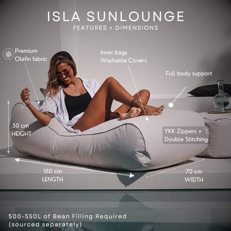 A woman reclines on a Natural Beige Isla Sunlounger, with overlaid text and measurement arrows showing dimensions: 180 cm length, 70 cm width, and 50 cm height. The image includes feature callouts such as premium olefin fabric, full body support, and YKK zippers plus double stitching.