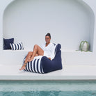 A woman sits on a navy blue and white striped Bora bean bag chair by Mooi Living, MOBORABB-STRI-NAV