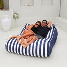 Couple relaxing together on a Navy Stripe Nevaeh double outdoor bean bag sunbed on a white patio, MOSTNEVBB-STRI-NAV
