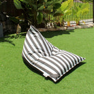 Mooi Living Oyster Black reversible triangle outdoor bean bag on grass, showing its oyster and black striped side, MOREVSTRIBB-BLASTR