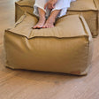 Tan canvas ottoman by Mooi Living positioned against a neutral wall.