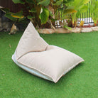 Mooi Living Taupe reversible triangle outdoor bean bag on grass, showing its plain taupe side with striped edging, MOREVSTRIBB-TPESTR
