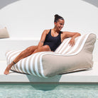 A beautiful lady relaxes poolside on a Taupe and white stripe Chill UV Lounger by Mooi Living, MOSTRCHILL-BB-TPESTR