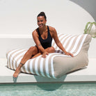 A beautiful lady relaxes poolside on a Taupe and white stripe Chill UV Lounger by Mooi Living, MOSTRCHILL-BB-TPESTR
