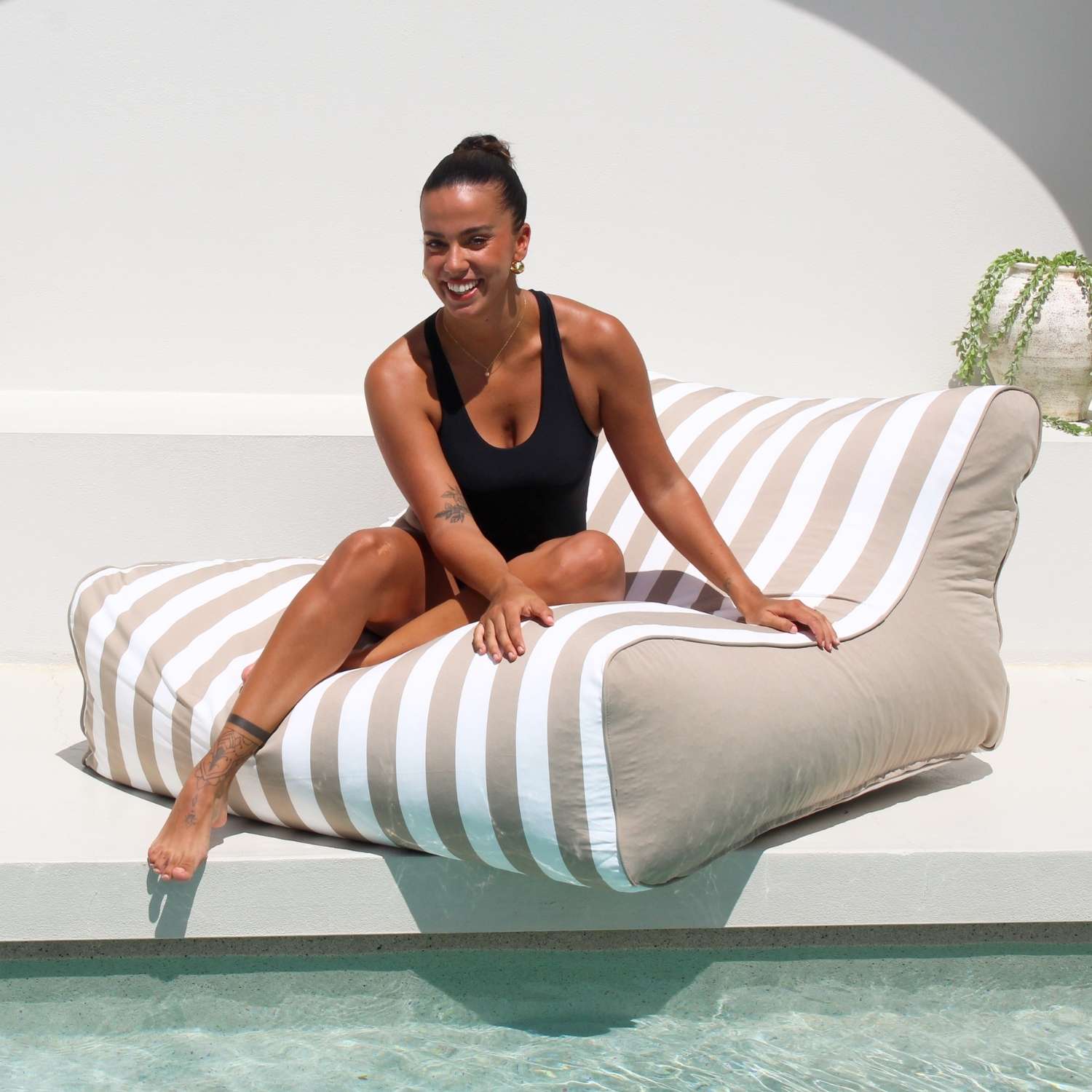 A beautiful lady relaxes poolside on a Taupe and white stripe Chill UV Lounger by Mooi Living, MOSTRCHILL-BB-TPESTR