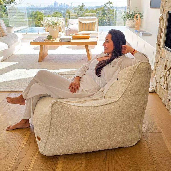 Contemporary neutral space featuring the Cream Bouclé Serena modern bean bag chair indoor bean bag by Mooi Living, with an adult seated.