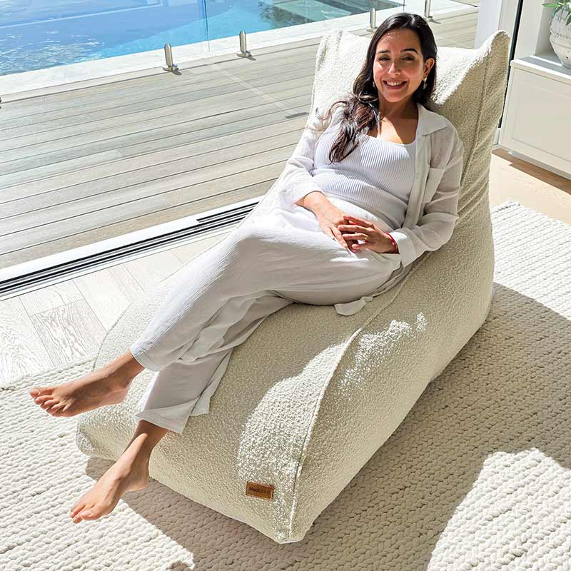 Cream bouclé indoor daybed by Mooi Living styled in a light-filled bedroom with woman seated.