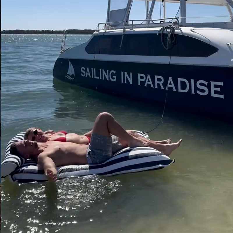 Santorini pool floating outdoor bean bag by Mooi Living beside a yacht from Sailing in Paradise Charters, luxury floating lounger in clear tropical water.