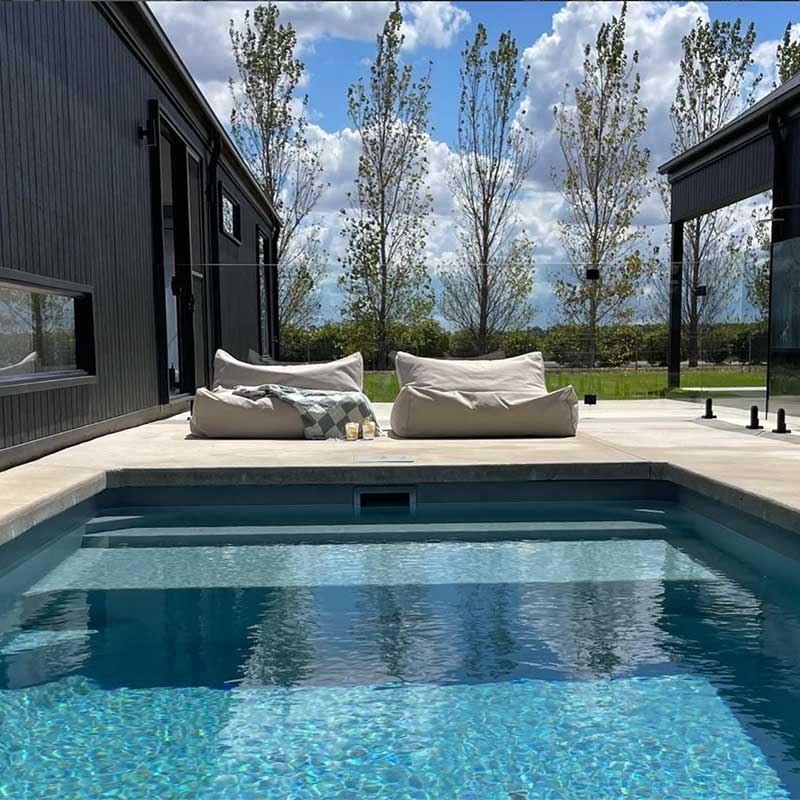 Two Natural Chill UV Loungers outdoor Bean Bag by Mooi Living. styled poolside beside a black home, customer photo by @jarlibarn