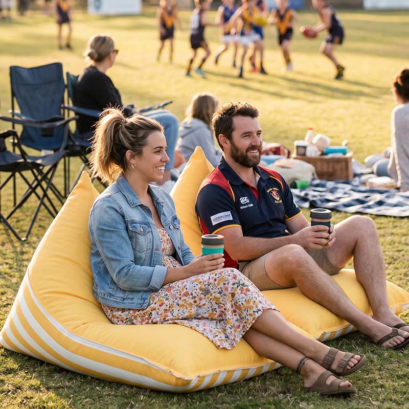 Couple sitting on a yellow Reversible Triangle outdoor bean bag by Mooi Living enjoying a casual outdoor gathering.