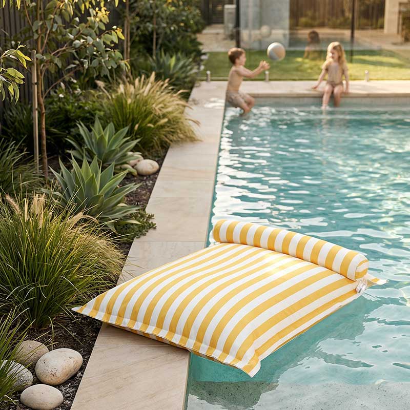 Children playing by a pool with a yellow striped Santorini Floating Outdoor Bean Bag by Mooi Living nearby