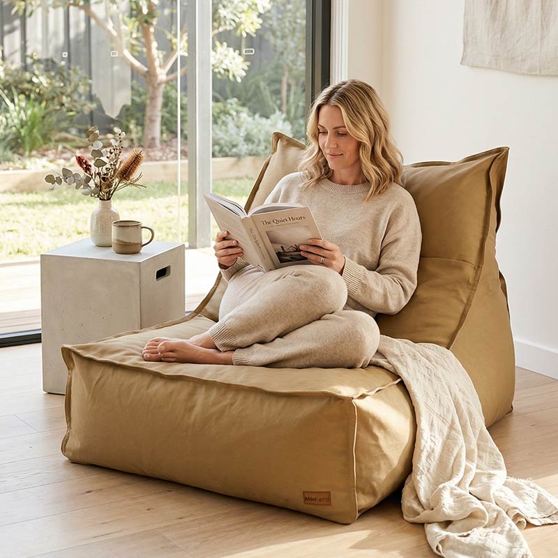 Lady sitting comfortably on a tan single boss bean bag chair indoor Bean Bag by Mooi Living, reading a book.